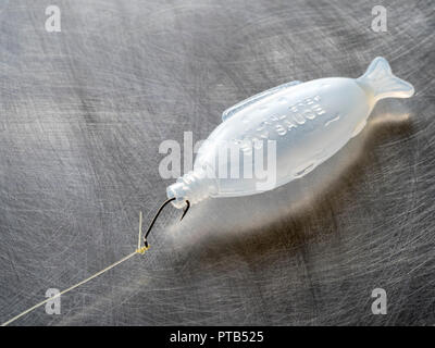 Leere Fisch geformt Sojasauce Flasche mit einem Angeln Haken gefangen in seinem Mund. Stockfoto