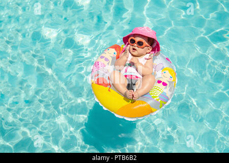 Cute Baby Mädchen in Sonnenbrille schwimmt auf Tropischen blauen Wasser Stockfoto