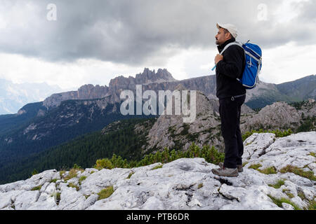 In der wunderschönen alpinen Landschaft eingebettet, ein Mann bewundert die hochalpine Landschaft mit Bergen und bewölktem Himmel. Stockfoto