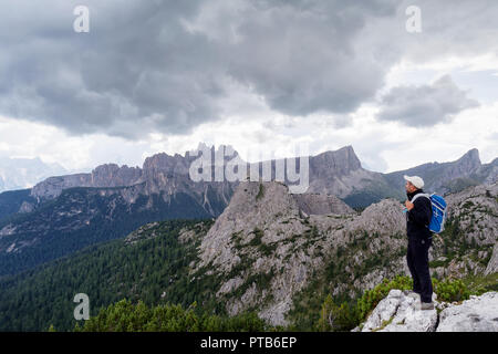 In der wunderschönen alpinen Landschaft eingebettet, ein Mann bewundert die hochalpine Landschaft mit Bergen und bewölktem Himmel. Stockfoto