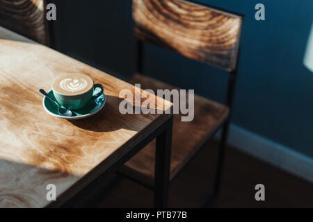 In der Nähe von frisch gebrühtem Kaffee Tasse auf hölzernen Tisch in moderne und helle Café. Stockfoto