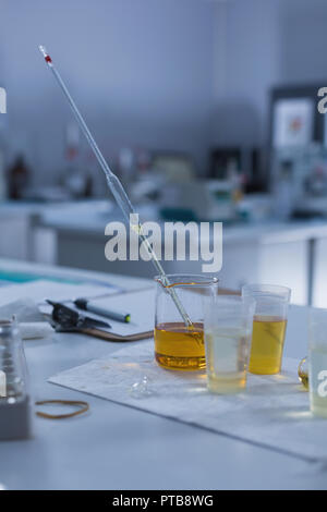 Becher, volumetrische Pipette und Zwischenablage auf Tisch Stockfoto