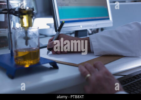 Männliche Wissenschaftler schreiben über die Zwischenablage im Labor Stockfoto