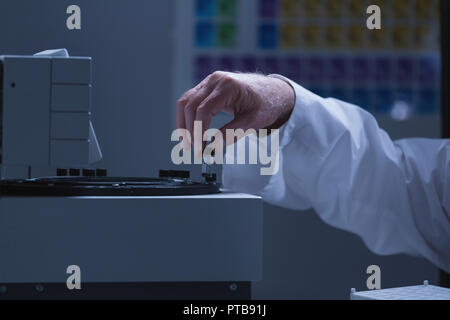 Männliche Wissenschaftler setzen chemische Rohr Glas Flasche auf einer Maschine Stockfoto