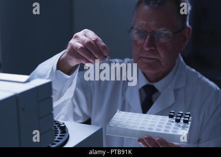 Männliche Wissenschaftler setzen chemische Rohr Glas Flasche auf einer Maschine Stockfoto