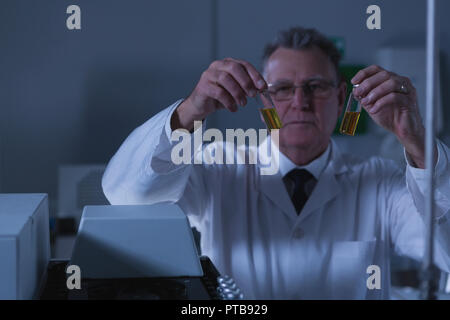 Männliche Wissenschaftler Platzierung von medizinischen Durchstechflaschen auf Lab Maschine Stockfoto