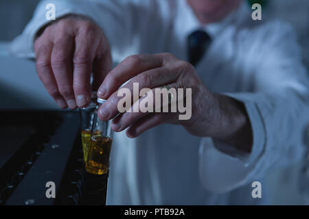 Männliche Wissenschaftler Platzierung von medizinischen Durchstechflaschen auf eine Übung Maschine Stockfoto