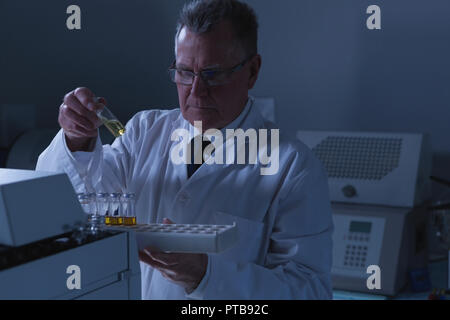 Männliche Wissenschaftler Platzierung von medizinischen Durchstechflaschen auf eine Übung Maschine Stockfoto