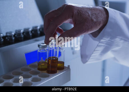 Männliche Wissenschaftler Platzierung von medizinischen Durchstechflaschen auf ein Labor im Labor Stockfoto