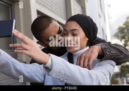 Mann küssen Frau unter selfie in der Stadt. Stockfoto