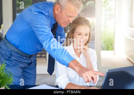 Schuss der Jungen financial Assistant Geschäftsfrau gemeinsam mit Executive Geschäftsmann. Junge professionelle Geschäftsfrau sitzen vor dem noteb Stockfoto