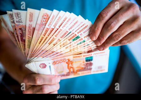 Russische Rubel in der Hand eines Lüfters. männliche Hand, die viele der Russischen Banknoten. Der Transfer von Geld. Die isolierten fünf Tausendstel der Russische Rubel Konfessionen in einer Hand Stockfoto