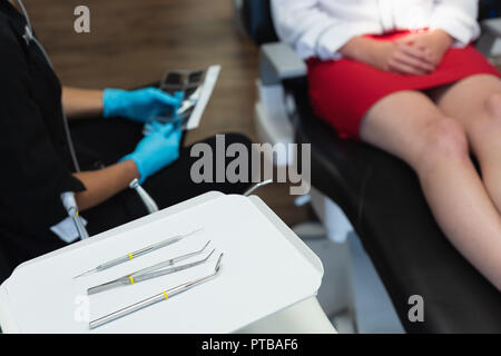 Zahnmedizinische Werkzeuge in das Fach, während die weiblichen Zahnarzt Interaktion mit Patienten Stockfoto