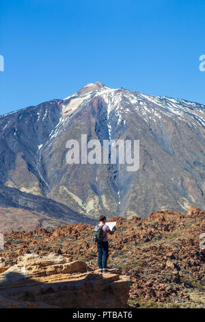 Verlorene Wanderer Kontrollen karte Wegbeschreibung stehen am Rand der Felsen mit Vulkan El Teide im Hintergrund finden. Nationalpark von Teneriffa, Kanarische Inseln, Stockfoto