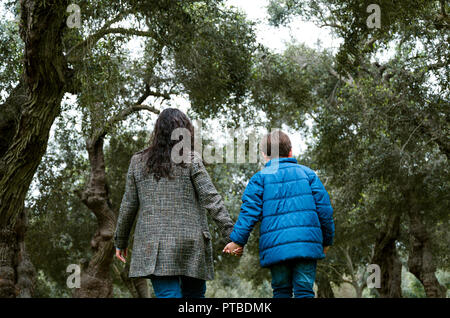 Mutter und Sohn Hand in Hand gehen in einen Park im Herbst Stockfoto