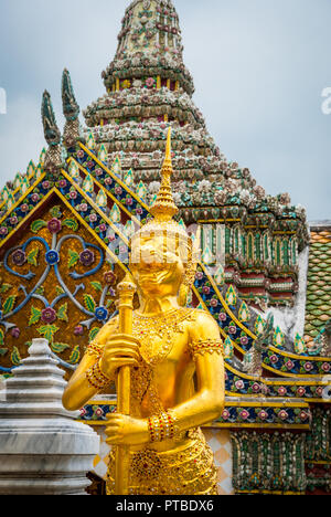 Goldene statue gegen bunte Pagode in Wat Phra Kaew Tempel, Bangkok, Thailand Stockfoto