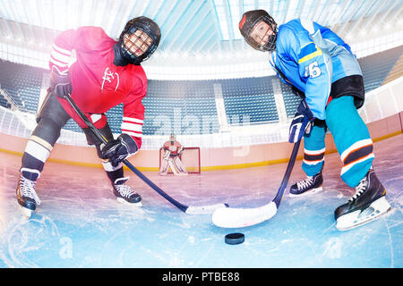 Low Angle Portrait von Jungen im Teenageralter, Eishockeyspieler, schwierig für den Puck auf der Eisbahn Stockfoto