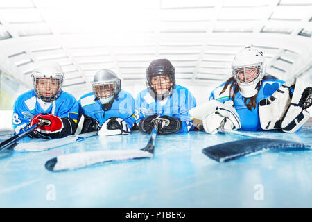 Porträt der jungen Hockeyspieler, Mädchen und Jungen, Festlegung auf der Eisbahn in der Linie Stockfoto