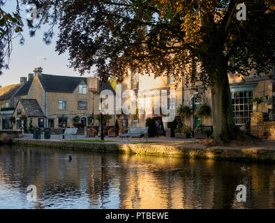 Die kingsbridge Inn und den Fluss Windrush am frühen Morgen Herbst Sonnenlicht. Bourton auf dem Wasser, Cotswolds, Gloucestershire, England Stockfoto