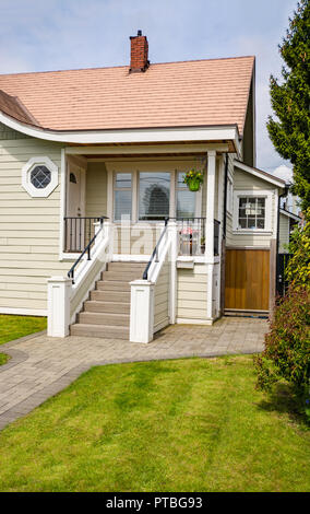 Haupteingang des kleinen Wohnhaus mit gepflasterter Weg über grüne