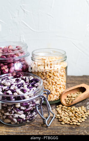 Sortiment von trockenen organischen Bohnen und Linsen in Gläsern auf rustikalen Holztisch. Vielzahl an raw Hülsenfrüchte. Ausgewogene Ernährung, Kochen, vegetarische und sauber Stockfoto