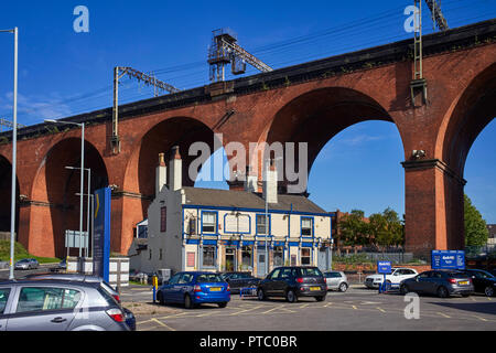 Crown Inn dwarfted und unterhalb der großen Backstein Eisenbahnviadukt in Stockport Stockfoto