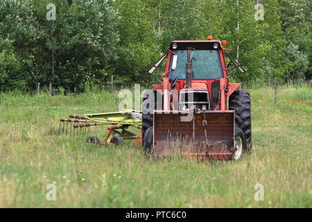 Quebec, Kanada. Farm Traktor mit Heu rechen im Feld geparkt Stockfoto