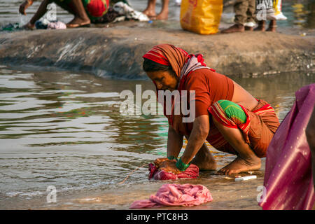 Traditionell gekleidete ältere Frau führt Ihre tägliche Routine von Hand ihre familys Waschen auf dem Felsen Ufer des Fluss Tungabhadra, Hambi, Stockfoto