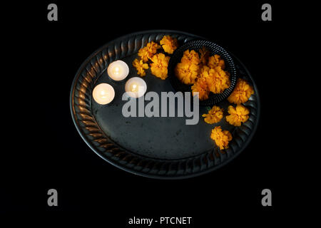 Dia de los Muertos, mexikanischen Tag der Toten Tabelle Szene. Orange tagetes, Ringelblumen Blumen und brennende Kerzen auf Vintage silver Fach Altar Zusammensetzung auf schwarzem Hintergrund. Halloween Flach, Ansicht von oben. Stockfoto