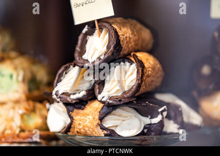 Nahaufnahme von Schokolade cannoli gefüllt mit Frischkäse sahne Füllung Dessert auf Glasplatte Fenster Anzeige in gourmet Bäckerei italienisches Café mit Golde Stockfoto