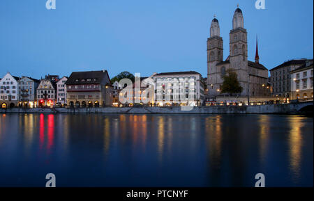 Ein Blick auf das Grossmünster Turm entlang der Limmat bei Dämmerung in Zürich, Schweiz. Stockfoto