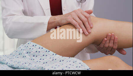 Ansicht schließen der leitenden Arzt zu jungen womans verletzten Knie tendenziell Stockfoto