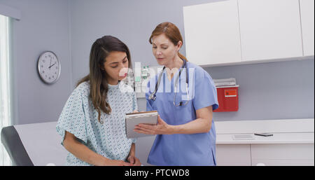 Im mittleren Alter Krankenschwester fragen Patienten Fragen über allgemeine Gesundheit Stockfoto