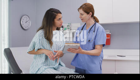 Im mittleren Alter Krankenschwester fragen Patienten Fragen über allgemeine Gesundheit Stockfoto