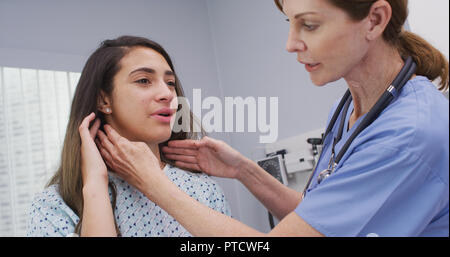 Leitende Krankenschwester untersucht womans Lymphknoten am Hals, um zu bestimmen, ob geschwollen Stockfoto
