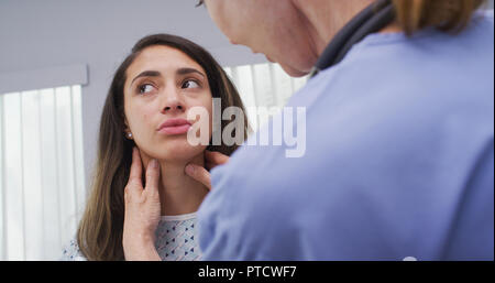 Leitende Krankenschwester Kontrolle der jungen Patienten Hals für geschwollene Lymphknoten Stockfoto