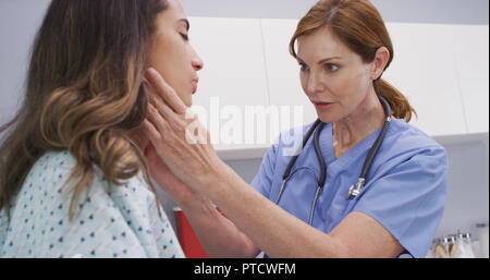 Leitende Krankenschwester untersucht womans Lymphknoten am Hals, um zu bestimmen, ob geschwollen Stockfoto