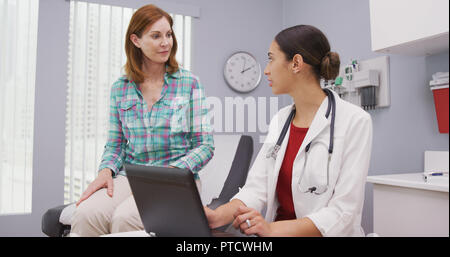 Nahaufnahme des mittleren gealterten Patienten diskutiert mit jungen weiblichen Arzt Gesundheit Ausgaben Stockfoto