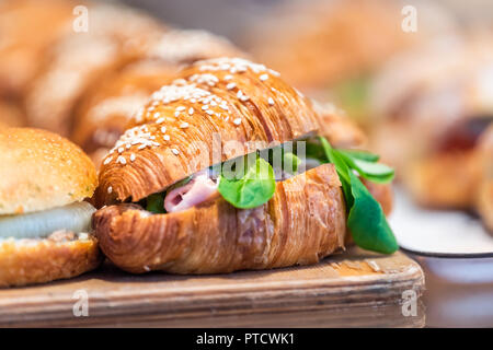 Nahaufnahme von herzhaften Frühstück croissant Sandwich golden Dessert in Bäckerei, Shop, Café, Shop Anzeige Fach mit Schinken, Rucola Grüns Stockfoto