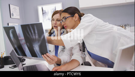 Zwei medizinische Ärzte anzeigen MRI-Scans des Patienten Hand drinnen Büro Stockfoto