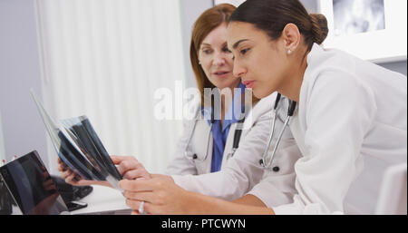 Junge Kollegen diskutieren Röntgenstrahlen mit dem Leitenden Arzt in Ihrem Büro Stockfoto