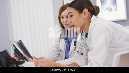 Junge Kollegen diskutieren Röntgenstrahlen mit dem Leitenden Arzt in Ihrem Büro Stockfoto