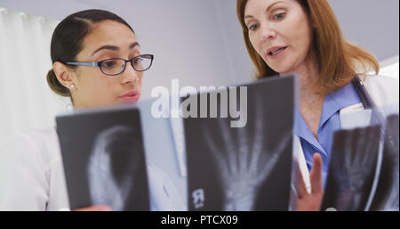Portrait von 2 Aerzte in Röntgenaufnahmen von Patienten Handgelenke suchen Stockfoto