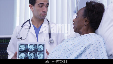 Charmante latino Arzt zeigen weibliche Patienten scans Ihres Gehirns auf Tablet PC Stockfoto