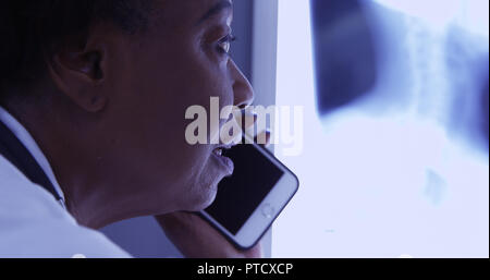 Mitte alter Schwarz MD Gespräch am Handy mit Patienten über x-ray Stockfoto