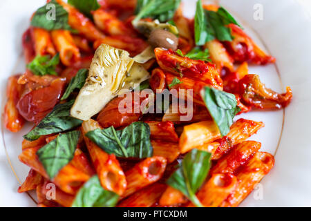 Flache Oberseite Tabelle, Nahaufnahme von frischen leuchtend rote Tomatensauce Nudeln Mais glutenfreie Nudeln auf dem Teller in marinara mit gehacktem Basilikum Grüns, articho Stockfoto