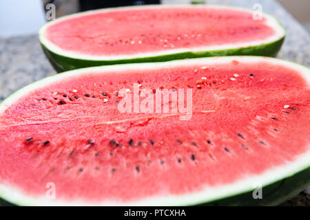 Nahaufnahme der beiden Hälften, Hälften der roten Wassermelone Halbieren mit Samen auf Küche Granit Arbeitsplatte Stockfoto