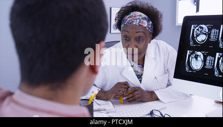 Senior afrikanischen Arzt Verschreiben von Medikamenten an männlichen Patienten mit Gehirn Anomalie Stockfoto