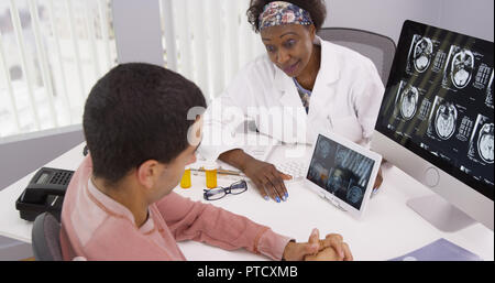 Ältere Schwarze Arzt erklären, männlichen Patienten die Nebenwirkungen einer Gehirnerschütterung Stockfoto