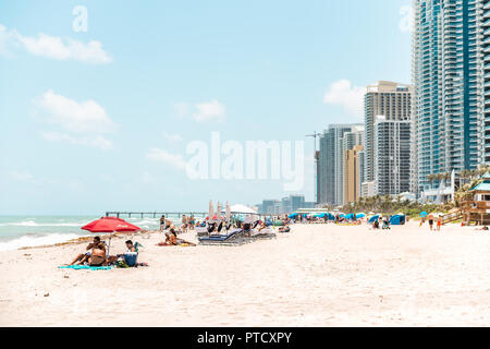 Sunny Isles Beach, USA - Mai 4, 2018: Strand mit Küste, Küste in der Nähe von Miami, Florida mit vielen Wohn-, Wohnung, Eigentumswohnung Gebäude, Menschen Stockfoto